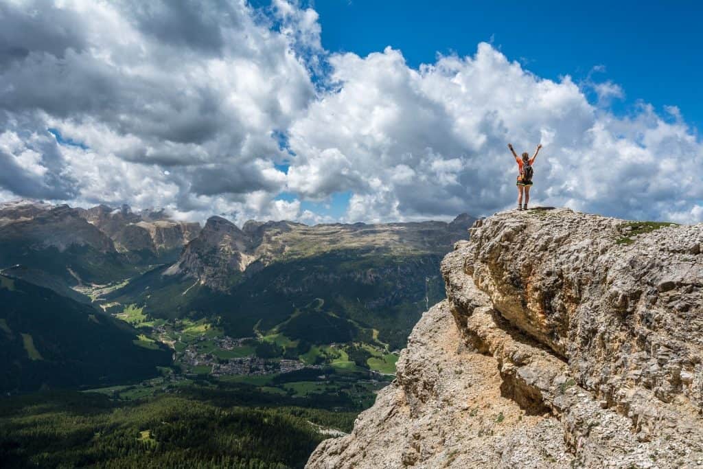 person spreading their arms for joy at mountain peak